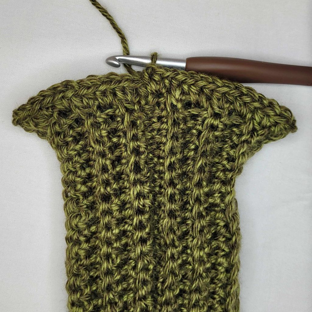 Instructional photo that shows how to make the Morgaine Sweater Scarf With Sleeves. 