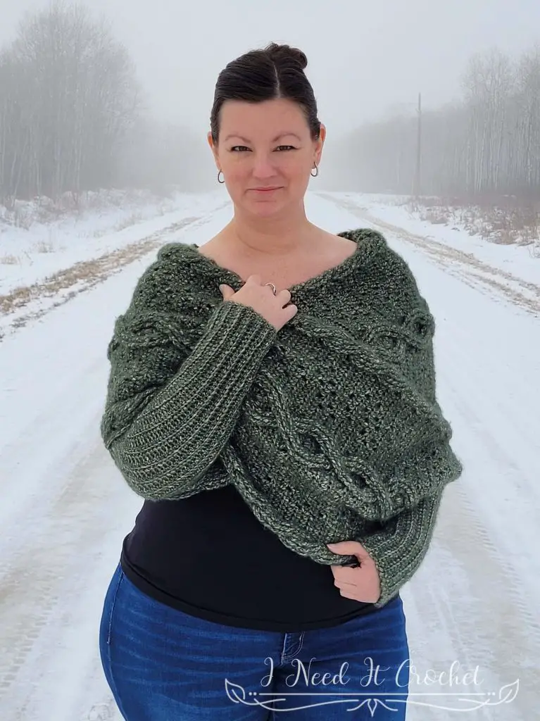 Picture of Morgaine Sweater Scarf With Sleeves. Pattern features a large cable running lengthwise down the middle, bordered with filet crochet and smaller crochet rope cables.