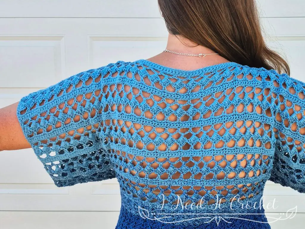 Slightly Slanted Blouse modeled with jeans, showing the lacy back and solid front crochet texture.
