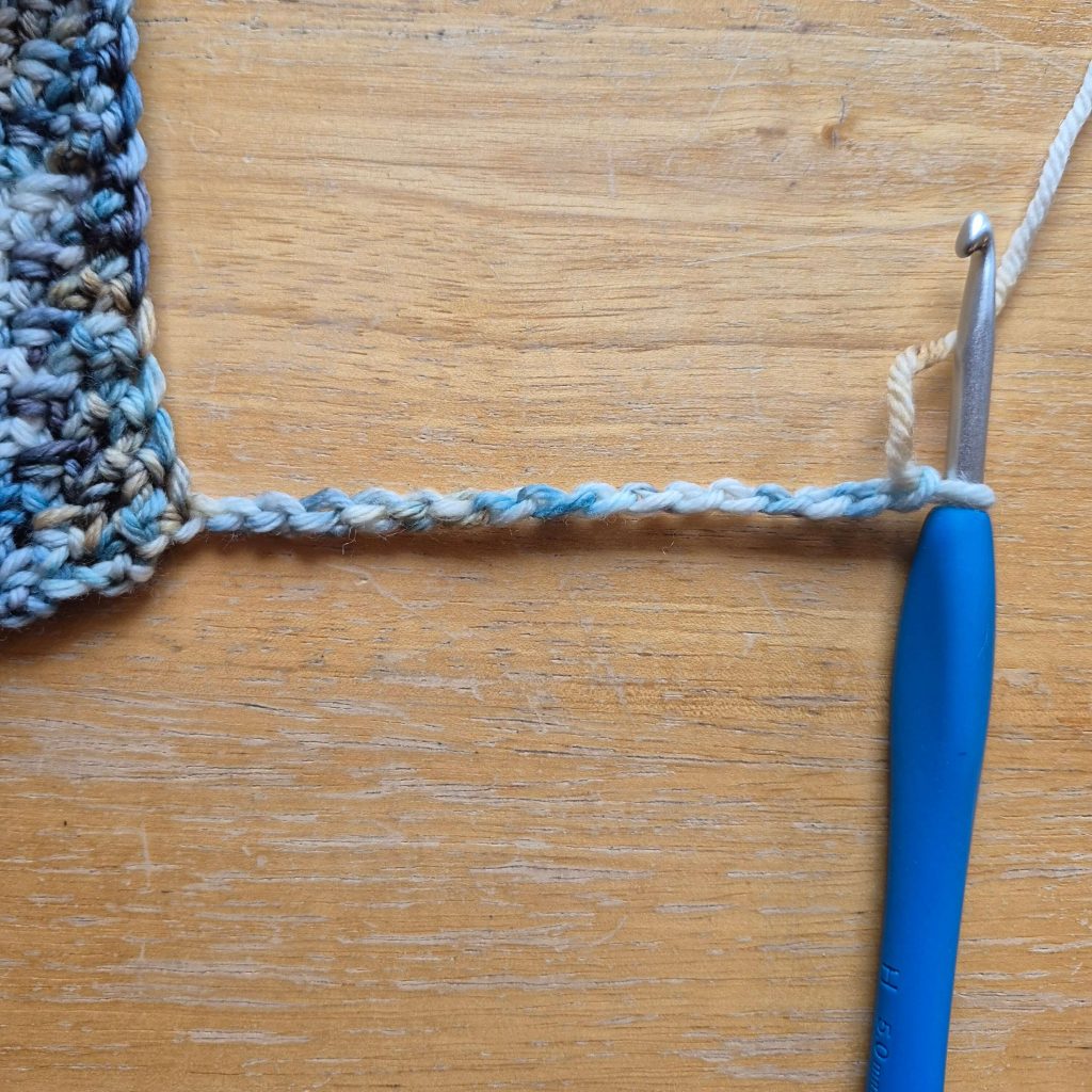 In-progress crochet sweater scarf showing textured fabric and stitch pattern