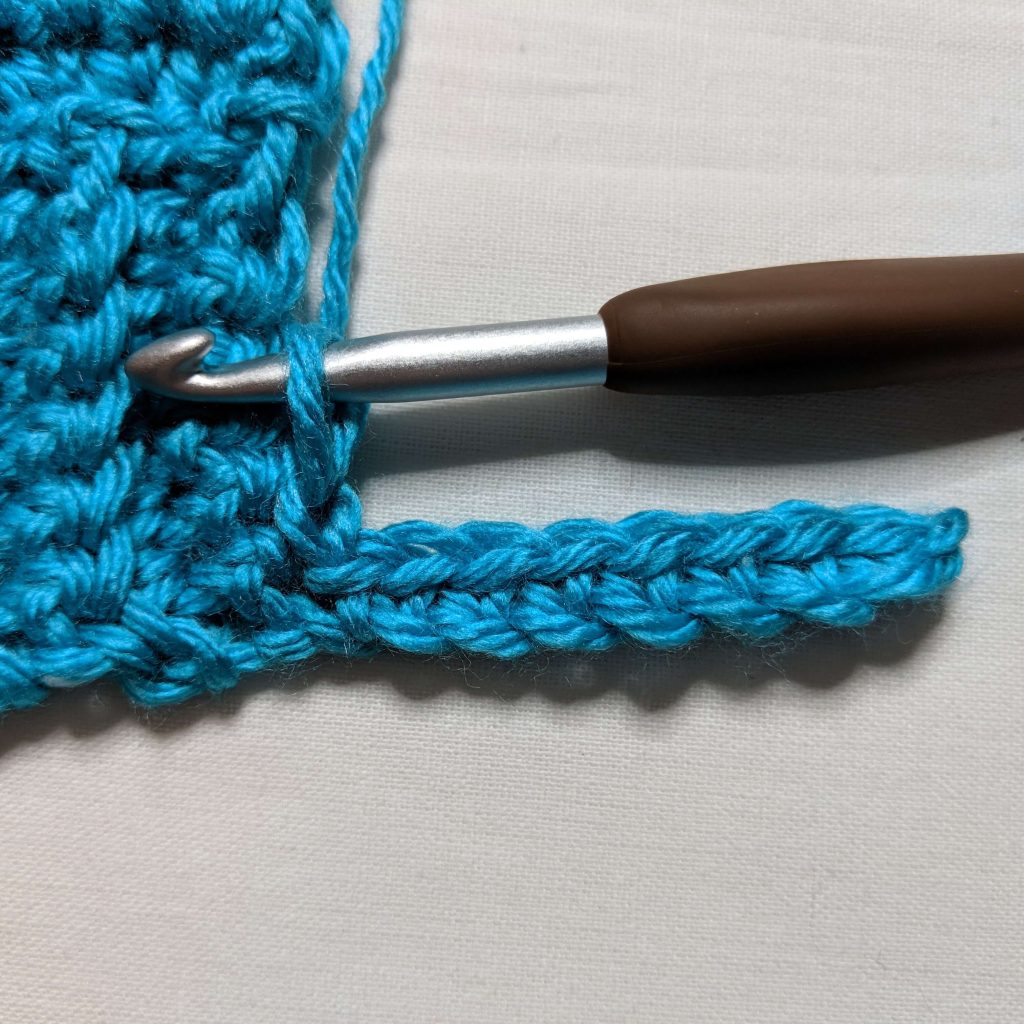 Slip stitching ribbed trim into front panel stitches of crochet cardigan